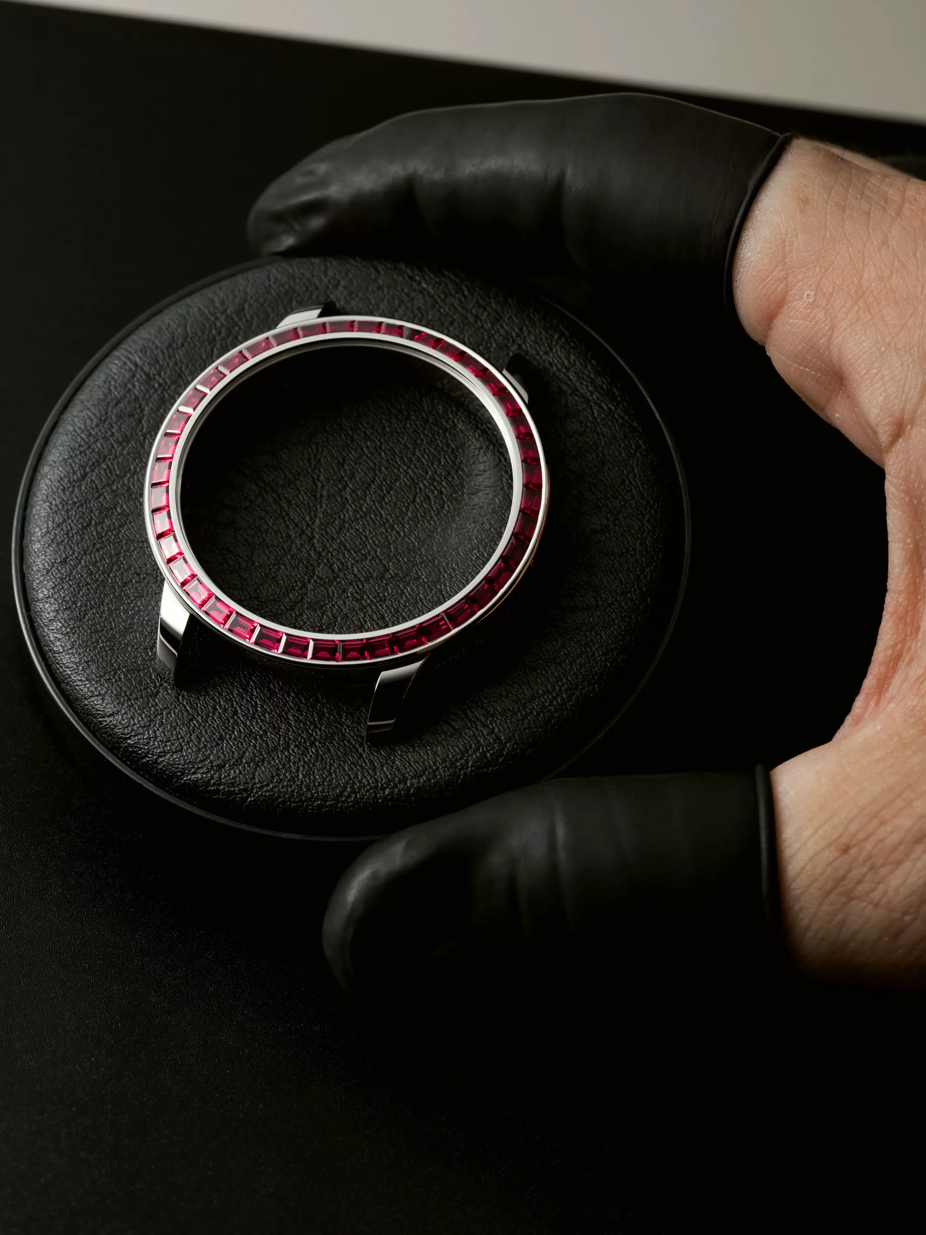 Ruby-set watch bezel held in a gloved hand