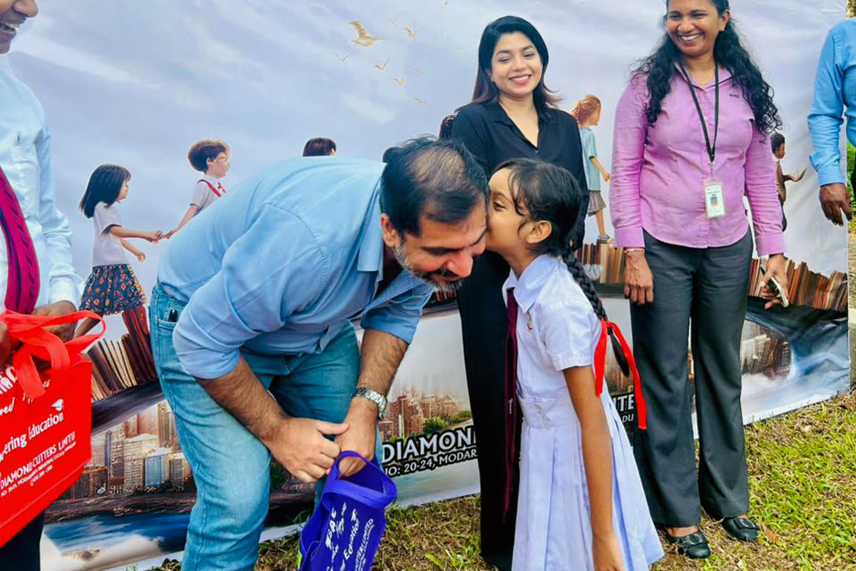 A NIRU colleague handing a school bag to a pupil at a NIRU Care education event in Sri Lanka