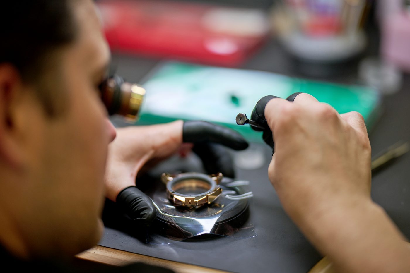 A gold watch opened on the bench, handled with gloves.