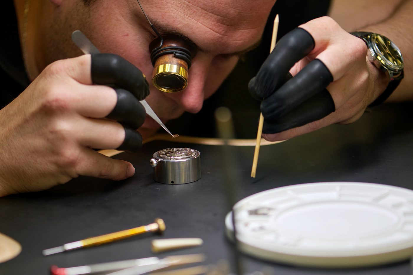 Tweezers at work on a movement held in its holder.