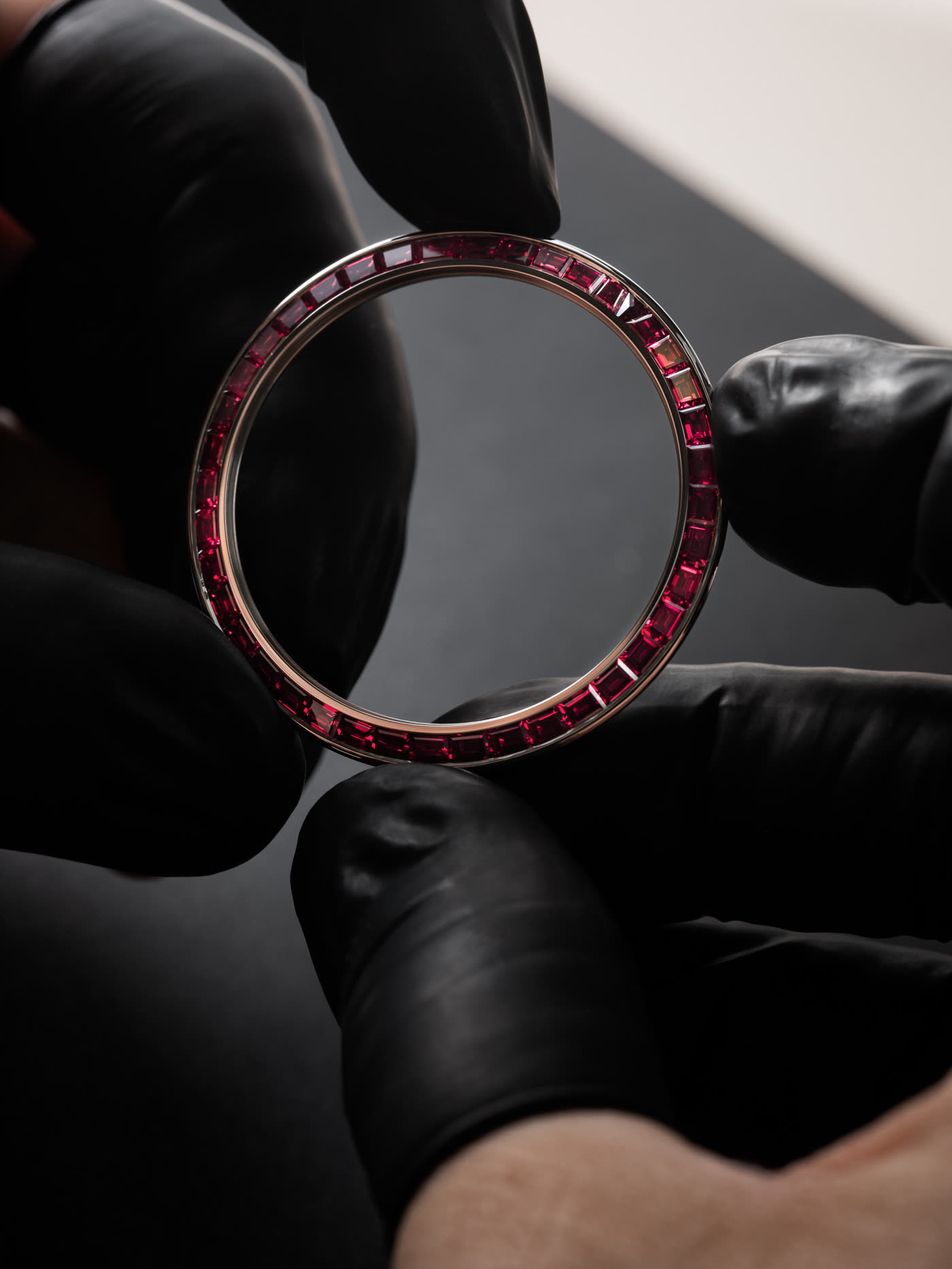A gloved hand holding the finished set bezel up to the light